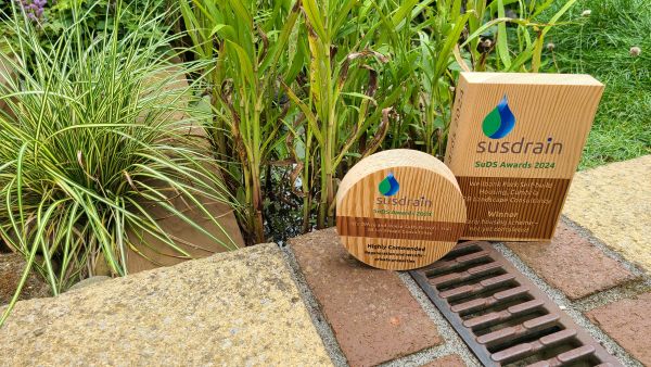 Two CIRIA Susdrain award trophies, next to a garden pond